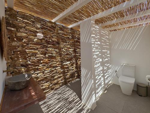 a bathroom with a stone wall and a toilet at Farous seaside sunset villa in Agios Georgios