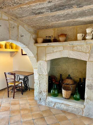 a stone oven with a table and some pots at Masseria Casina Montana in Corigliano dʼOtranto