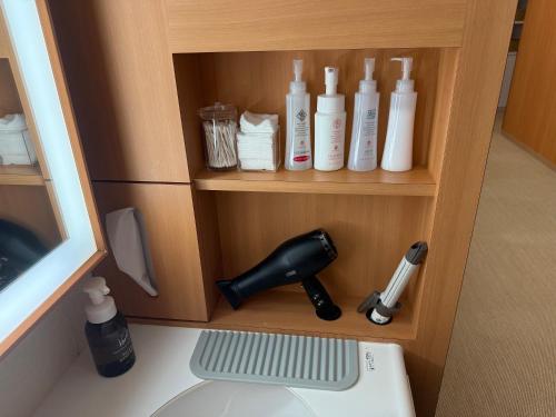 a shelf with bottles and a hair dryer on it at First Cabin Nishi Umeda in Osaka
