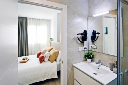 un bagno con un letto, un lavandino e uno specchio di REM II Torrevieja a Torrevieja