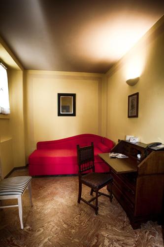 a living room with a red couch and a piano at Locanda Chi Ghinn in Verbania