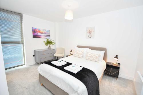 a white bedroom with a large bed and a window at Modern 2 Bed Flat in Central Manchester w Balcony in Manchester