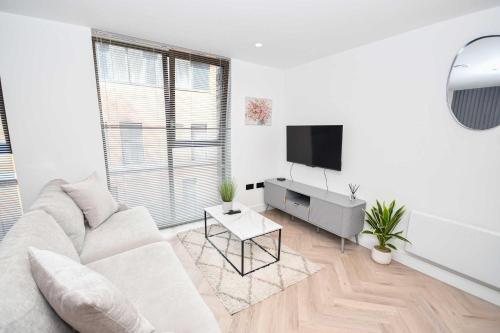 a white living room with a white couch and a tv at Modern 2 Bed Flat in Central Manchester w Balcony in Manchester