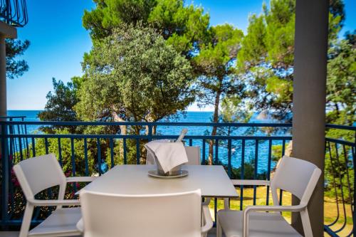 un tavolo bianco e sedie su un balcone con vista sull'oceano di Arena Verudela Beach a Pola (Pula)