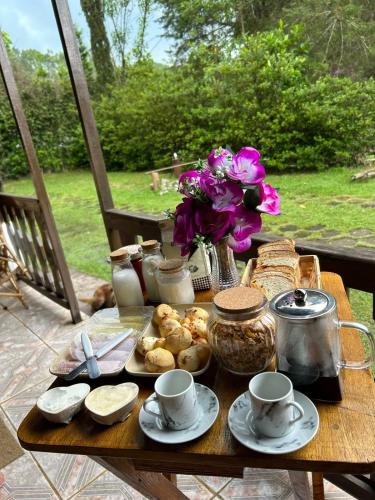 un tavolo con cibo e tazze e fiori di Chalé Estância do Coruja a Salesópolis