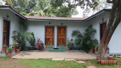 a small white house with a wooden door at Disha Villa in Alibag