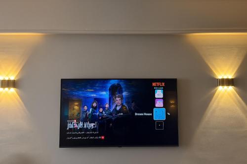 a flat screen tv on a wall with two lights at Nasr City Airport شقة فاخرة مدينة نصر in Cairo