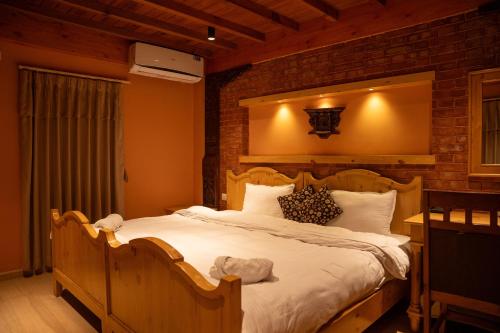 a bedroom with a large bed with a brick wall at Nag Pukhu Guest House in Bhaktapur