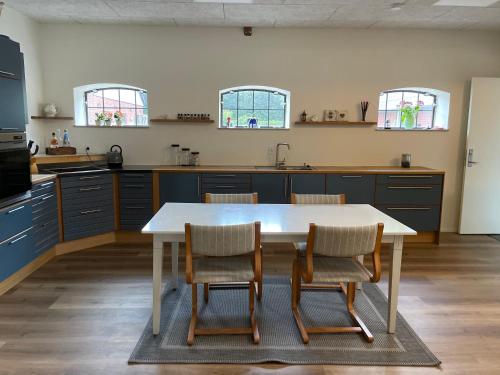 a kitchen with a white table and chairs in it at Højmosegård HEMS in Varde