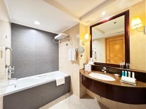 a bathroom with a sink and a tub and a mirror at The Bellevue Manila in Manila