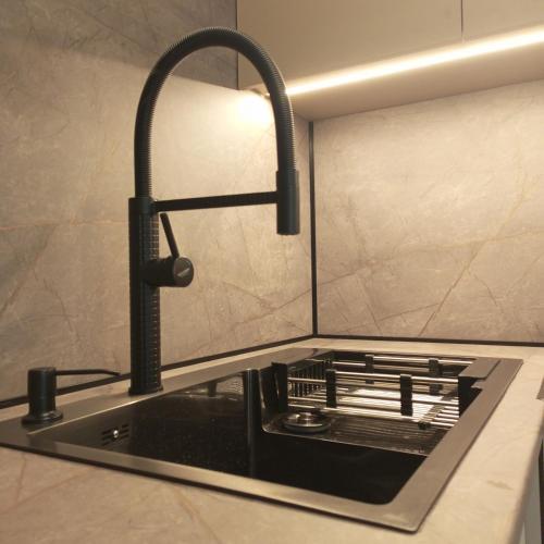 a kitchen sink with a faucet and a stove at New apartment near the PALM tree in Uzhhorod