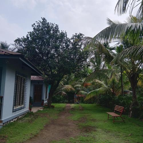 a house with a bench next to a yard with palm trees at Disha Villa in Alibag