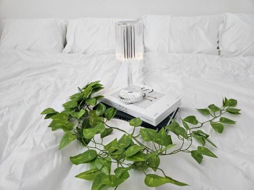 a lamp on a book on a bed with a plant at Luna House in Gangneung