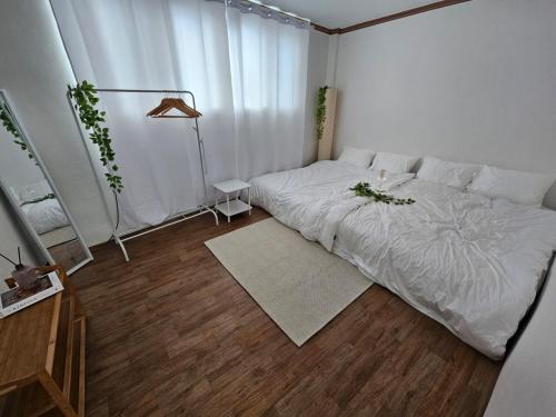a bedroom with a white bed and a wooden floor at Luna House in Gangneung