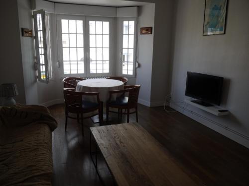 sala de estar con mesa, sillas y TV en Appartement Chaussee du Sillon, en Saint-Malo