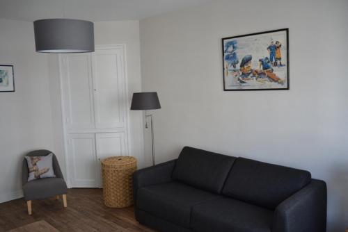 Appartement Chaussee du Sillon في سان مالو: غرفة معيشة مع أريكة سوداء وكرسي