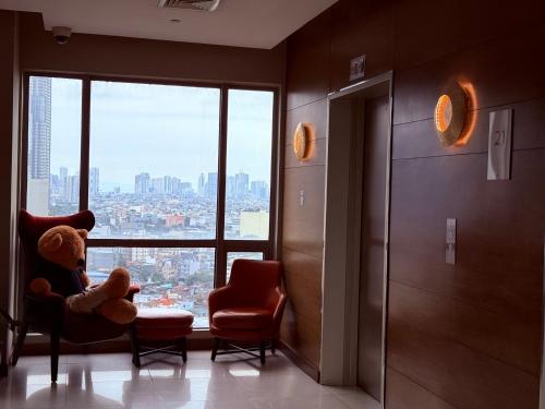 a teddy bear sitting in a chair in a room with a window at Hotel Residences at ACQUA Tower near Rockwell Makati in Manila