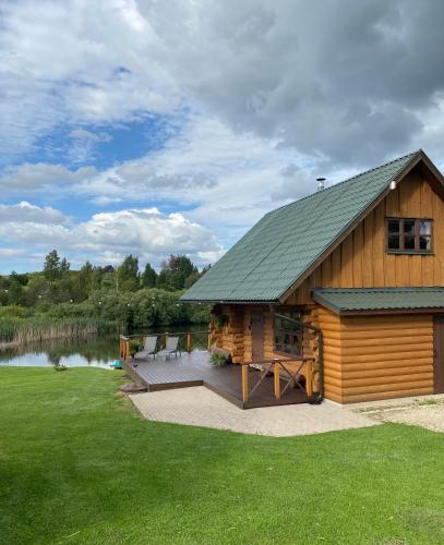 a log cabin with a deck next to a lake at Tatra Holiday House in Tatra