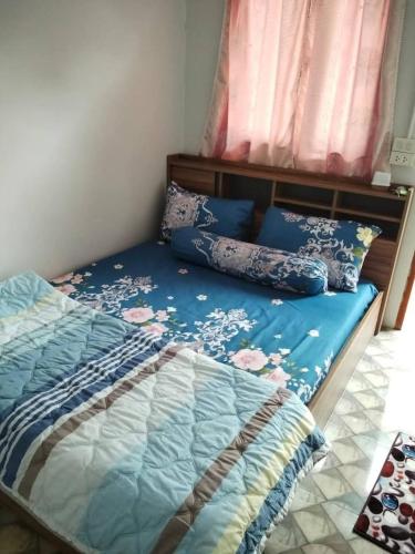 a bedroom with a bed with blue sheets and pillows at Economy double room with fan only and external bathroom facilities in Ban Chak Khamin