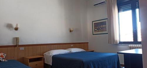 a room with two beds and a window and a table at Albergo Le Rose in Pistoia