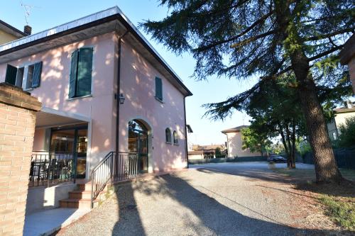 a white building with a tree next to a street at Hotel Vignale in Vignale
