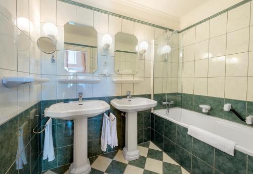 ein Badezimmer mit zwei Waschbecken und einer Badewanne in der Unterkunft Corneli Residenties - Chateau St Gerlach in Valkenburg