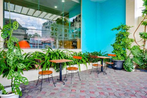 a group of tables and chairs in a room with plants at Sans Hotel Nagari Malioboro in Yogyakarta