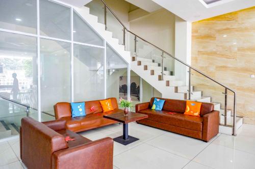 a living room with two leather couches and a table at Sans Hotel Nagari Malioboro in Yogyakarta