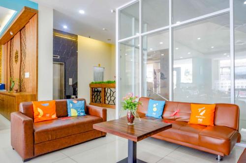 a living room with two leather couches and a table at Sans Hotel Nagari Malioboro in Yogyakarta