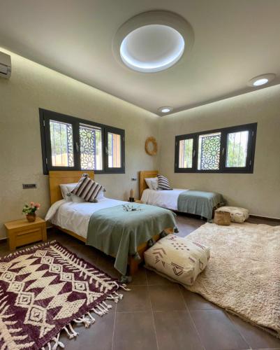 a bedroom with two beds and a rug at Shams Ourika in Sbiti