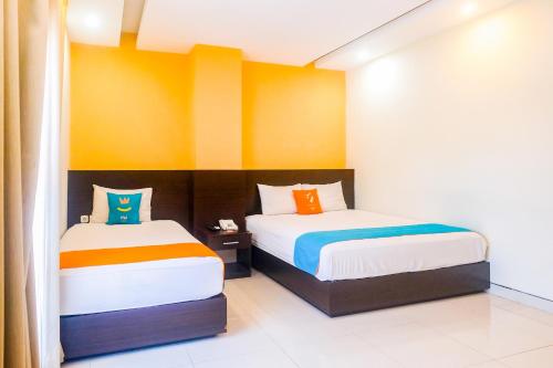two beds in a room with yellow and orange walls at Sans Hotel Nagari Malioboro in Yogyakarta