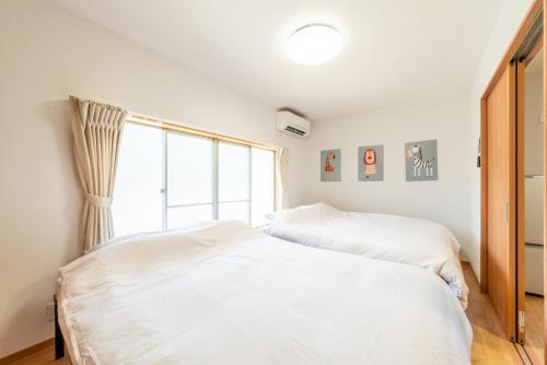 a bedroom with two white beds and a window at 大和の宿 Kitabukuro201 in Nara