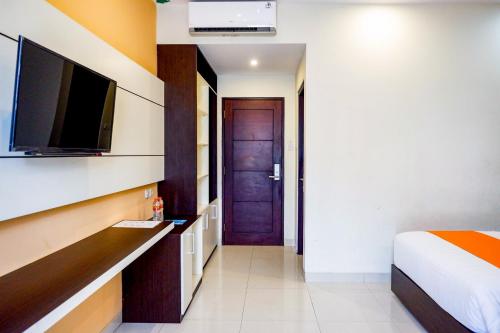 a bedroom with a bed and a tv and a door at Sans Hotel Nagari Malioboro in Yogyakarta