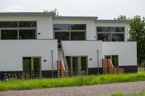 a white building with green doors and windows at Kooparc vakantiepark in Giesbeek