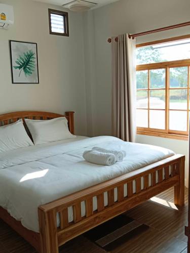 a bedroom with a large wooden bed with a window at Minimal Pool Villa Chiang Mai in Chiang Mai