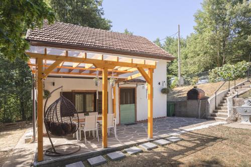 a pergola with a swing in front of a house at Vikendica WoodNook Kosmaj - Šumski kutak in Sopot