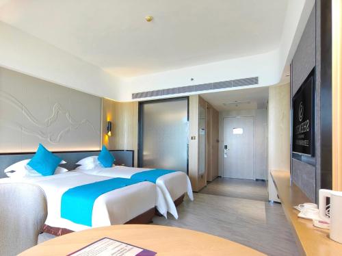 a hotel room with two beds and a television at Shengyi Holiday Villa Hotel in Sanya