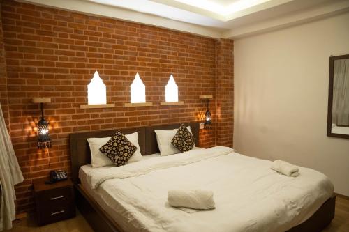 a bedroom with a large bed with a brick wall at Nag Pukhu Guest House in Bhaktapur