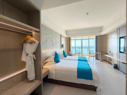 a bedroom with a bed and a view of the ocean at Shengyi Holiday Villa Hotel in Sanya