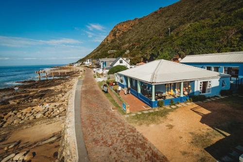 a blue house on the beach next to the ocean at Silver Spray Beach Accommodation in Victoria Bay