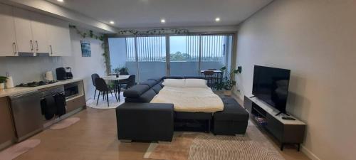 a living room with a bed and a kitchen at Stylish 1Bedroom Apartment with Study and Parking Near Sydney Airport in Sydney