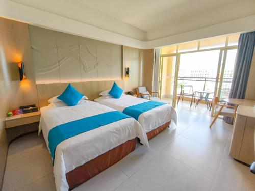 a hotel room with two beds and a balcony at Shengyi Holiday Villa Hotel in Sanya