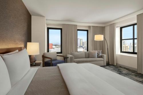 a hotel room with a bed and a couch and windows at The Westin San Diego Gaslamp Quarter in San Diego
