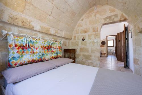 a bedroom with a bed in a stone wall at Casa Varvodda in San Vito dei Normanni