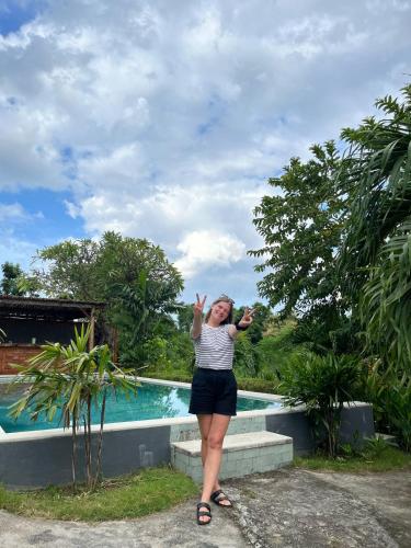 a woman standing in front of a swimming pool at Eco Moringa Garden in Banyuwedang