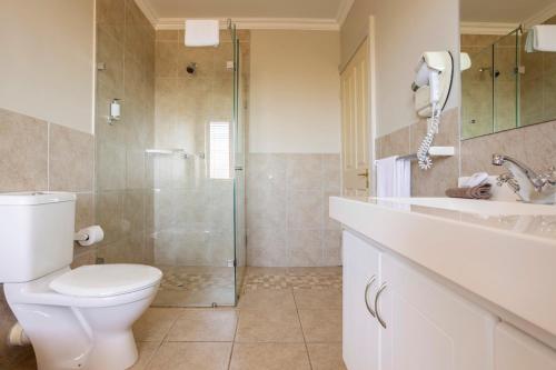 a bathroom with a toilet and a glass shower at Devonvale Golf & Wine Estate in Stellenbosch