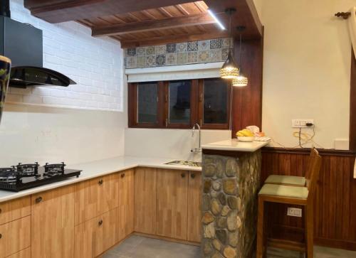 a kitchen with wooden cabinets and a window at Hridayam Homestay near Mukteshwar in Mukteswar