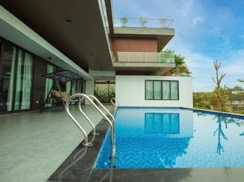 a swimming pool in front of a house at FLAMIGO ĐẠI LẢI RESORT - Villa View Hồ in Ngọc Quang