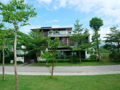 a large building with trees in front of it at FLAMIGO ĐẠI LẢI RESORT - Villa View Hồ in Ngọc Quang
