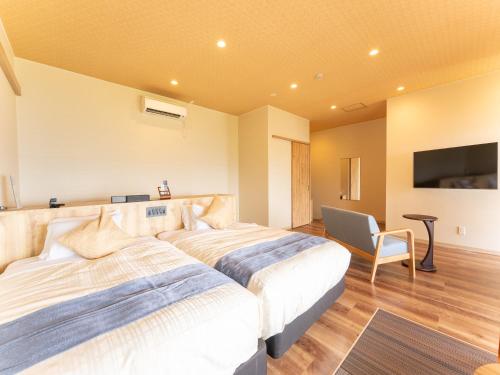 a hotel room with two beds and a chair at Livemax Resort Inami Seafront in Inami